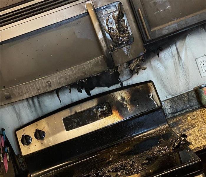 charred remnants of a residential microwave and stove from a house fire